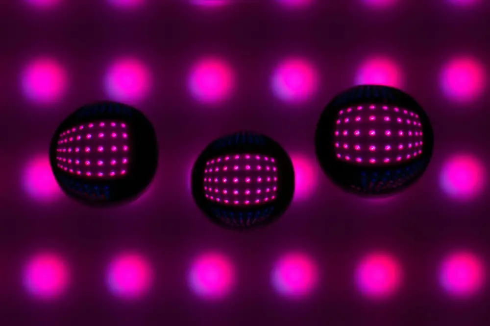 Three glass spheres reflecting a grid of pink lights