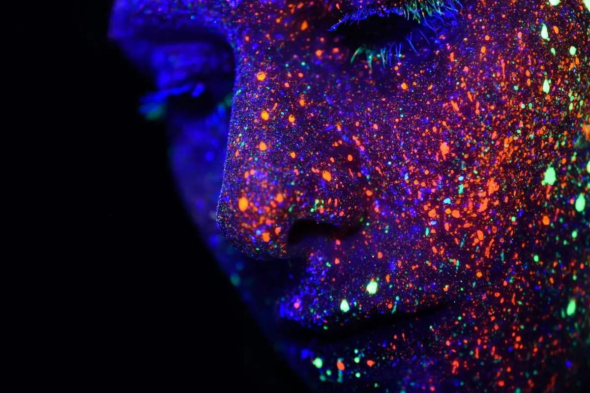 Close-up of a face covered in glowing fluorescent paint
